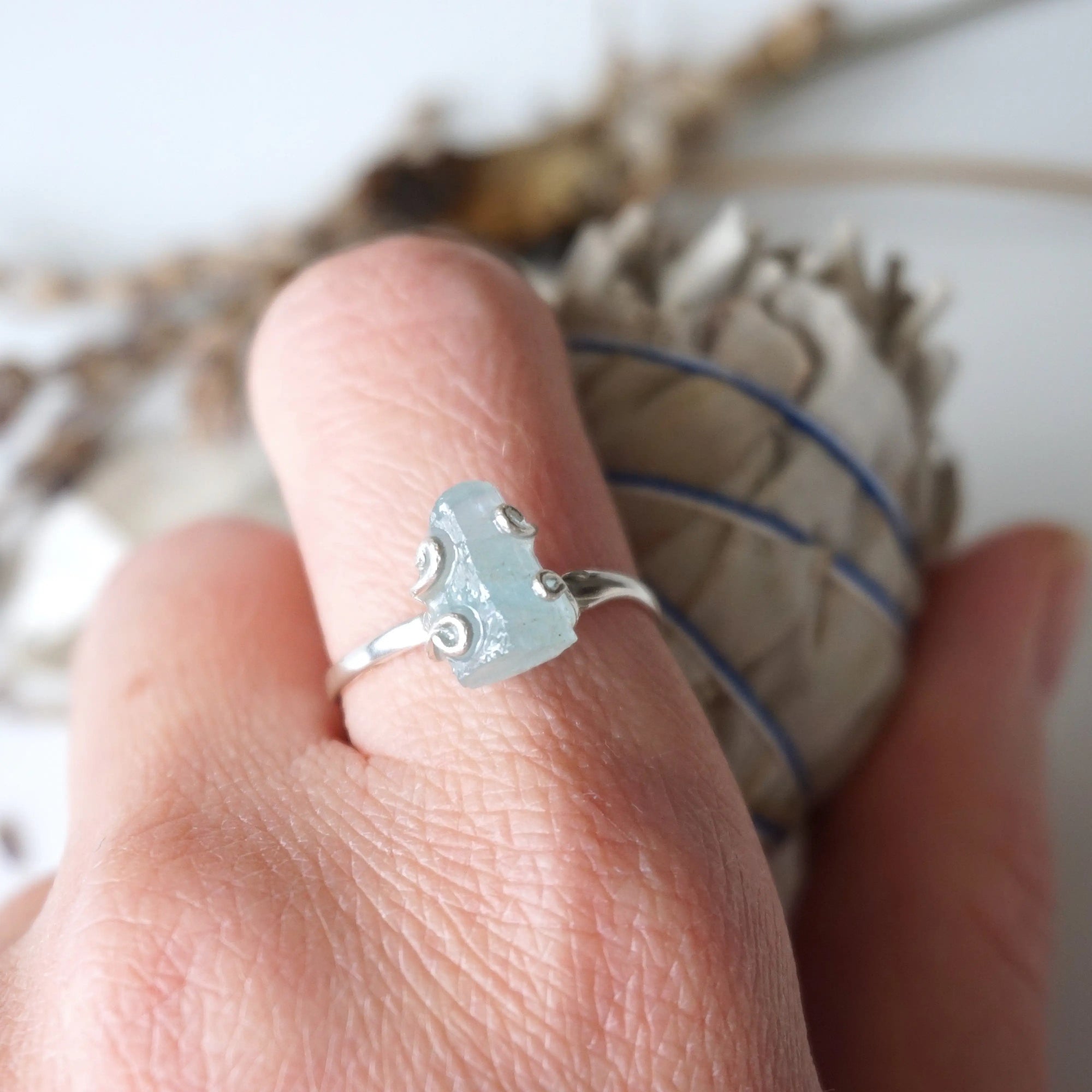 Adjustable aquamarine ring with raw gemstone in 925 sterling silver prong setting on female model's hand, Designs by Nature Gems