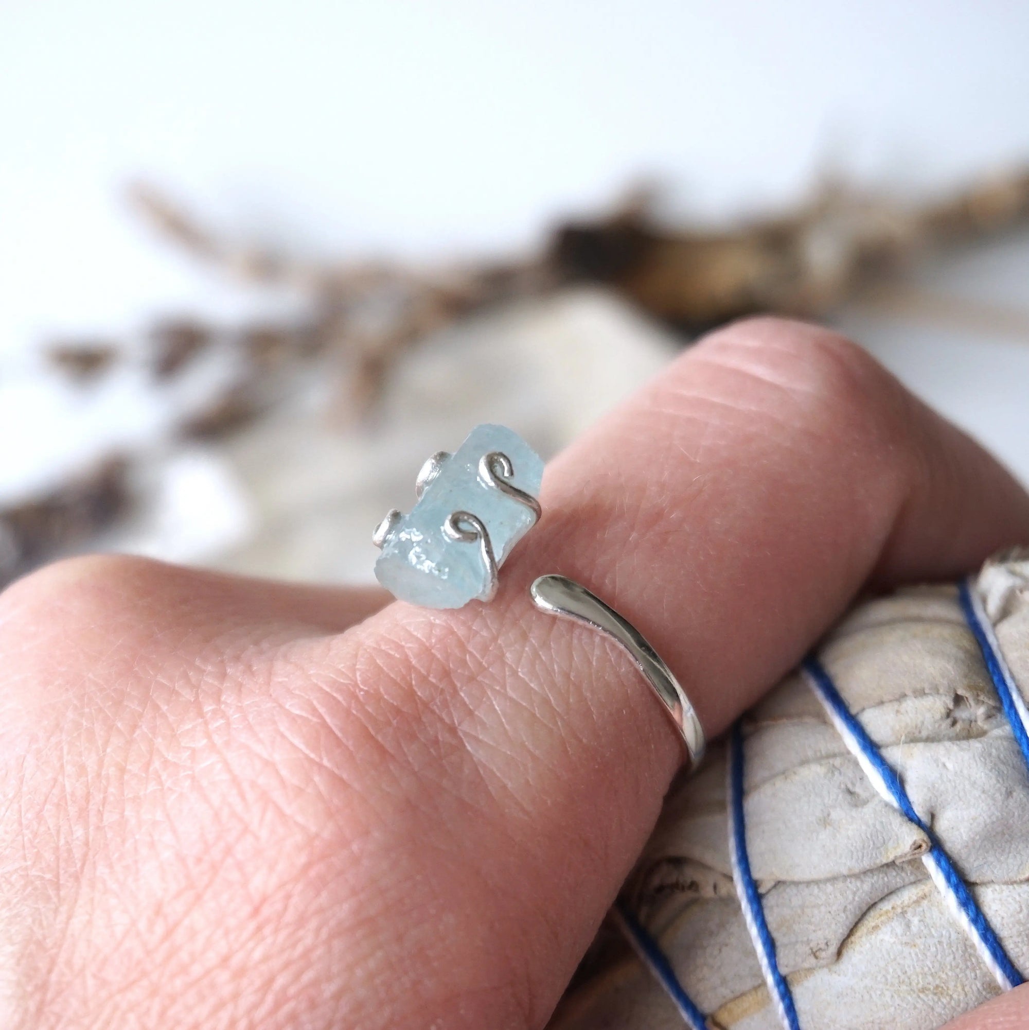 Adjustable aquamarine ring with raw gemstone in 925 sterling silver prong setting on female model's hand, Designs by Nature Gems