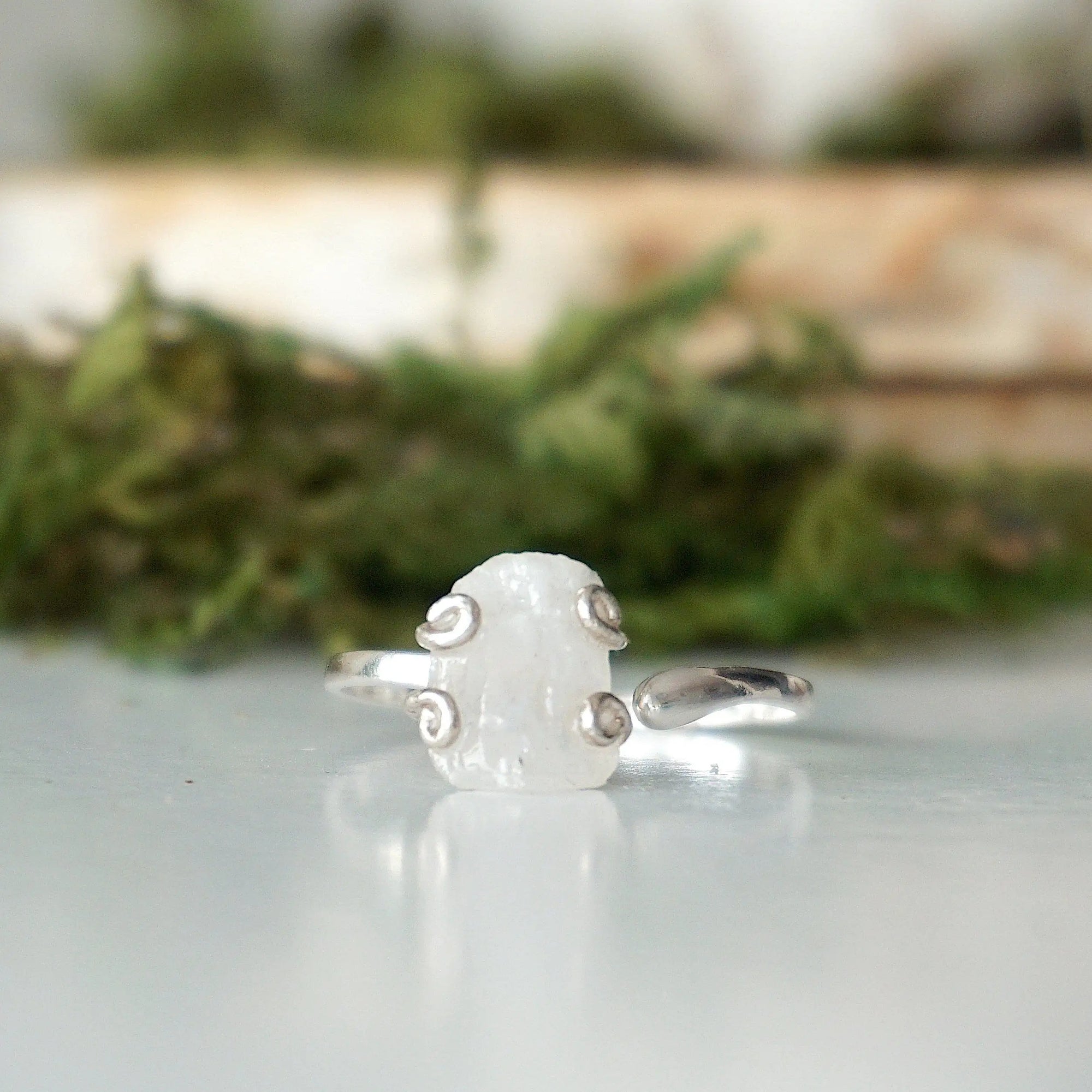 Close-up front view of raw rainbow moonstone stone in artisan 925 sterling silver adjustable ring setting, June birthstone ring.