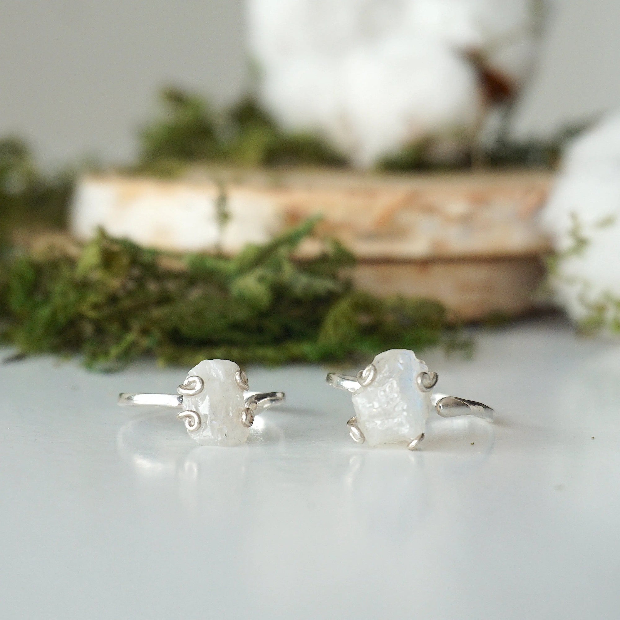 Two adjustable raw rainbow moonstone rings showing natural variation in stone size, shape, and moonstone flash in sterling silver settings.