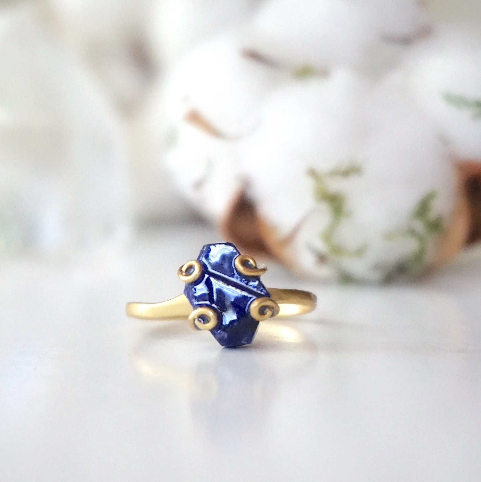 Front view of adjustable raw sapphire ring focused on the natural blue stone and gold vermeil artisan setting