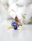 Front view of adjustable raw sapphire ring focused on the natural blue stone and gold vermeil artisan setting