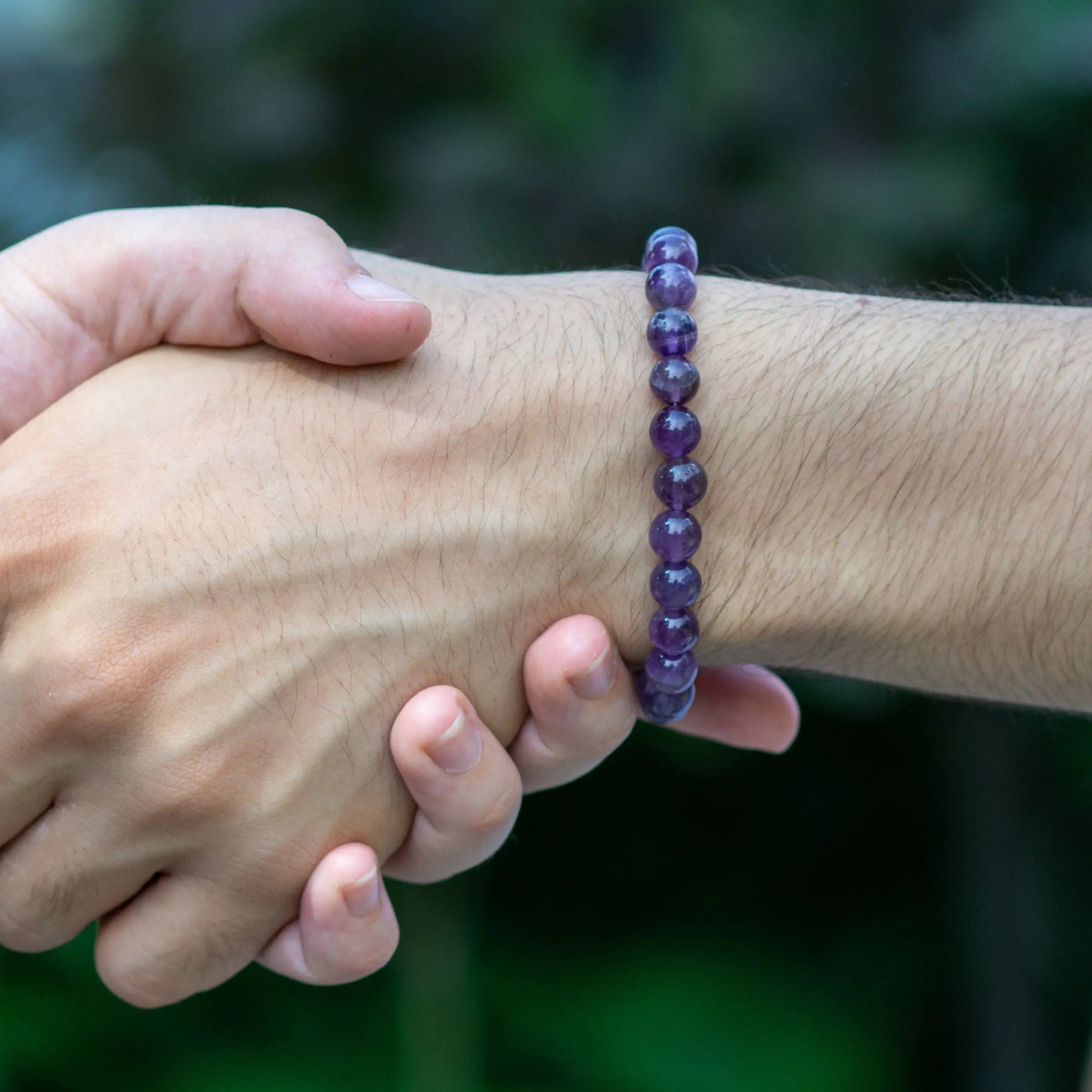 Amethyst beaded stretch bracelet on male model's wrist, natural 8mm amethyst beads, unisex style