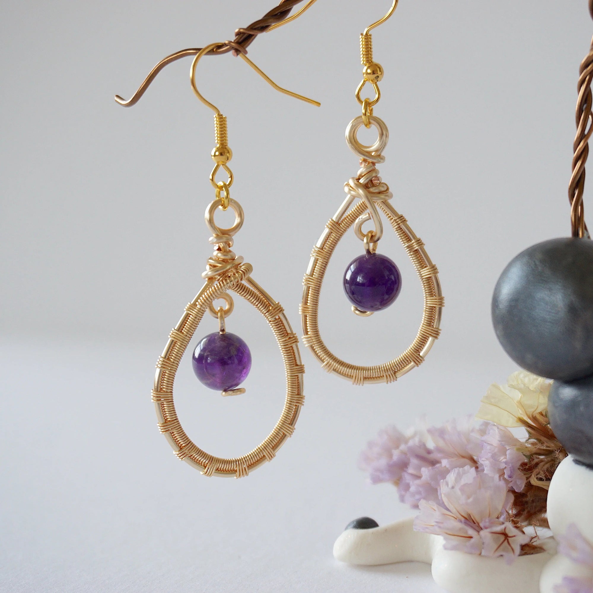 Closeup of gold plated copper wire wrapped amethyst teardrop earrings showing 8mm polished February birthstone bead and details