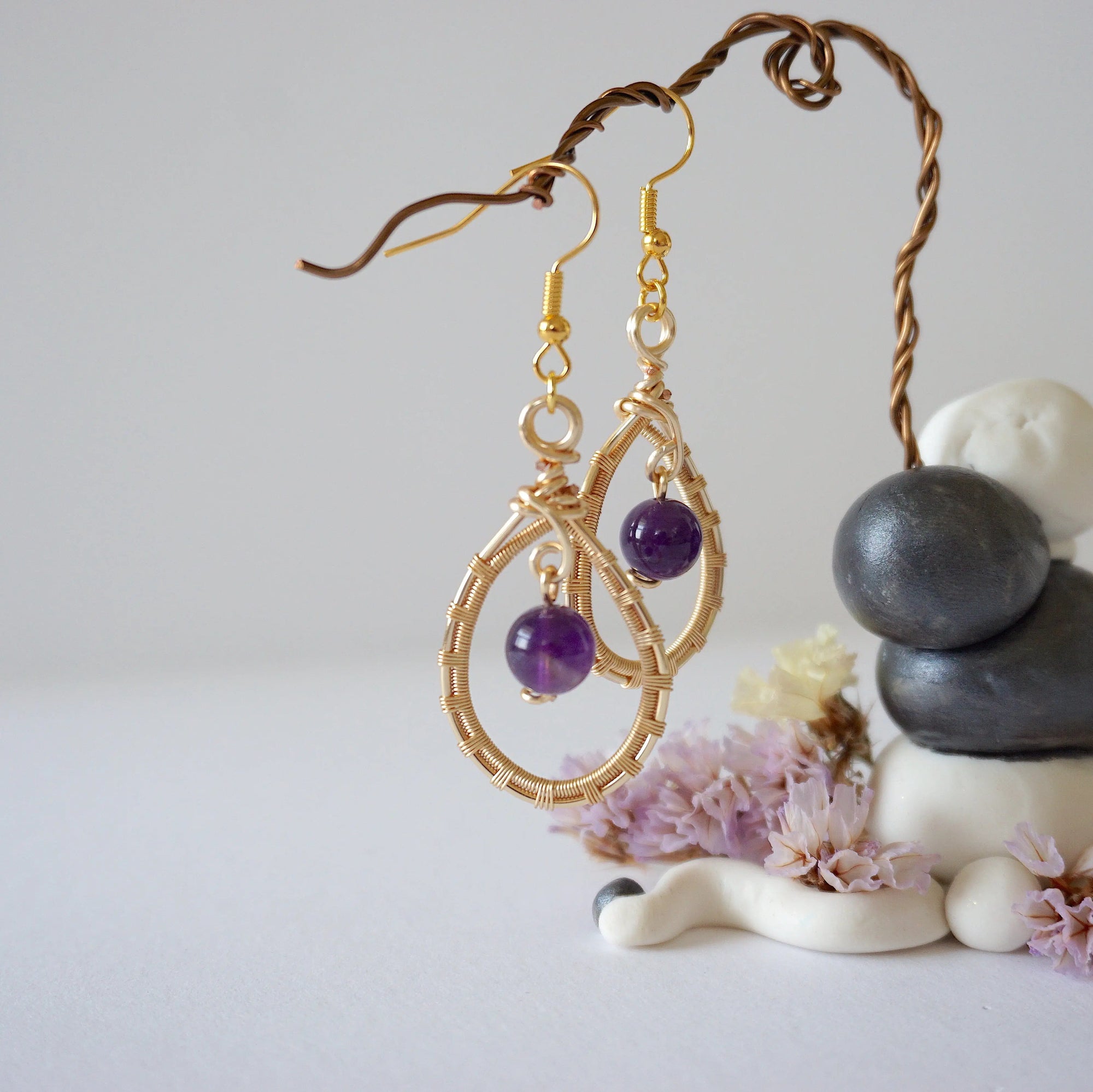 Side view of wire wrapped amethyst dangle earrings in gold plated copper with fish hook ear wires and teardrop frame