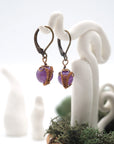 Side angle of amethyst drop earrings on a display stand, highlighting antique bronze copper wire wrapping.