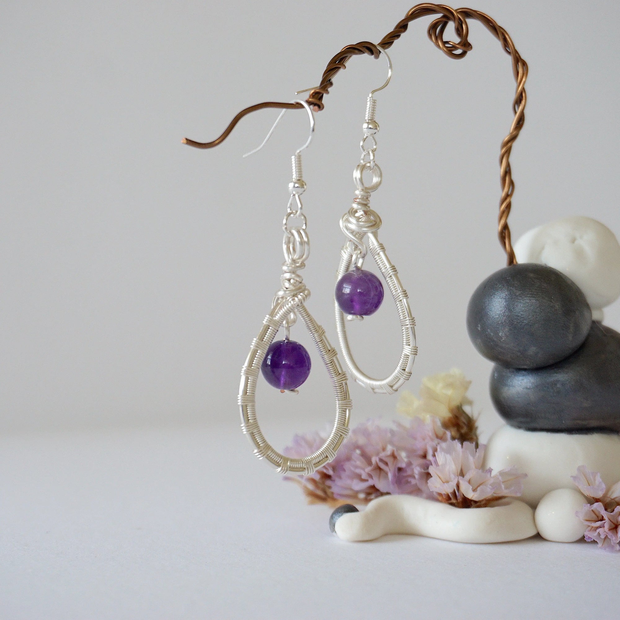 Closeup of silver plated copper wire wrapped amethyst teardrop earrings showing 8mm polished February birthstone bead and details