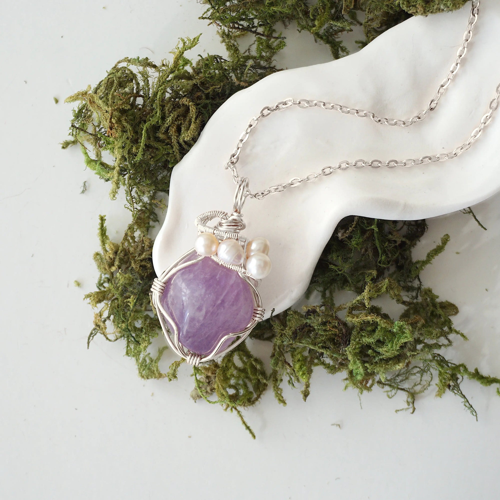 Handmade silver wire wrapped amethyst and freshwater pearl necklace laying flat on a silver plated chain, artisan jewelry for women