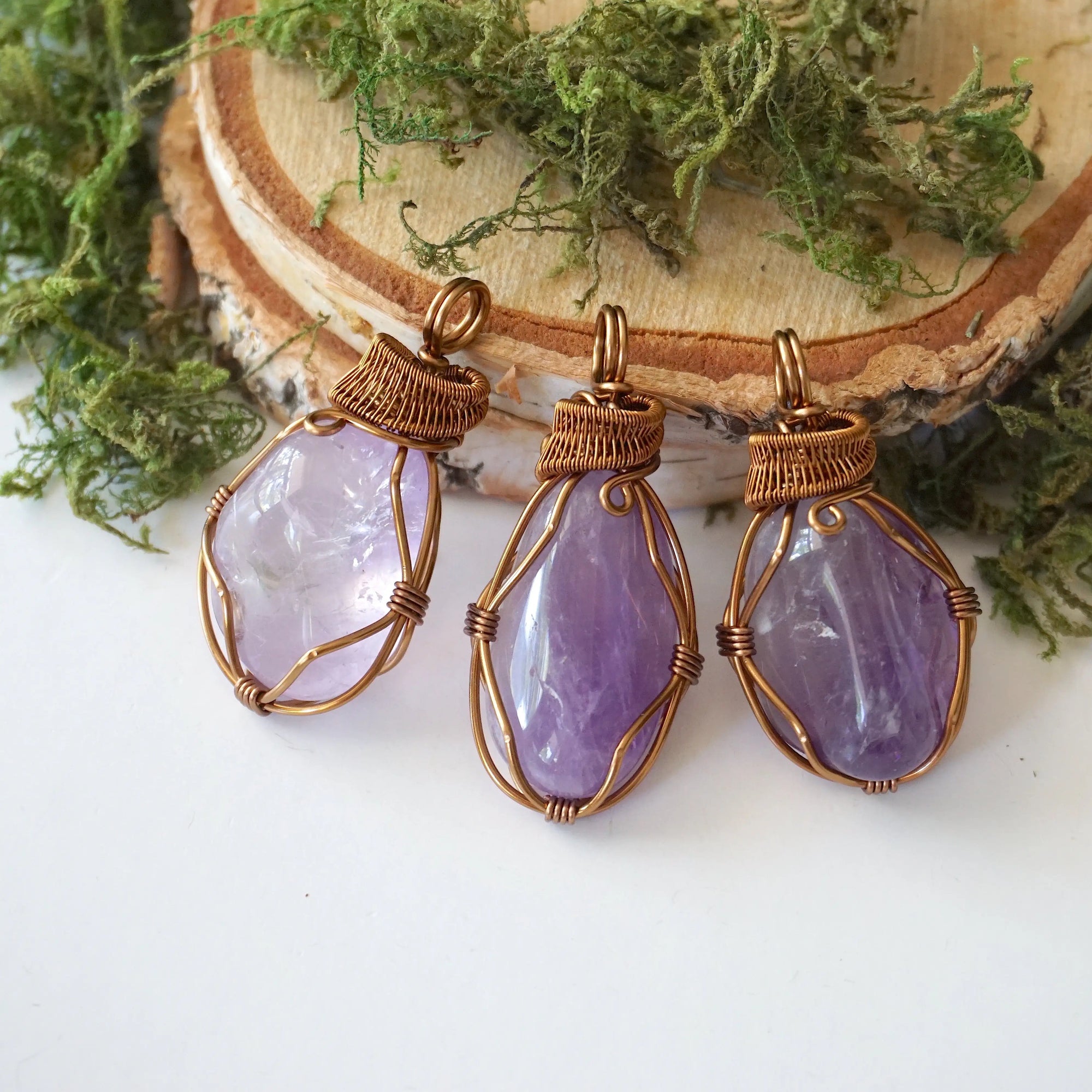 Three women’s amethyst necklaces showing natural variation in lighter violet amethyst stone size, shape, and color, antique bronze copper wire wrap