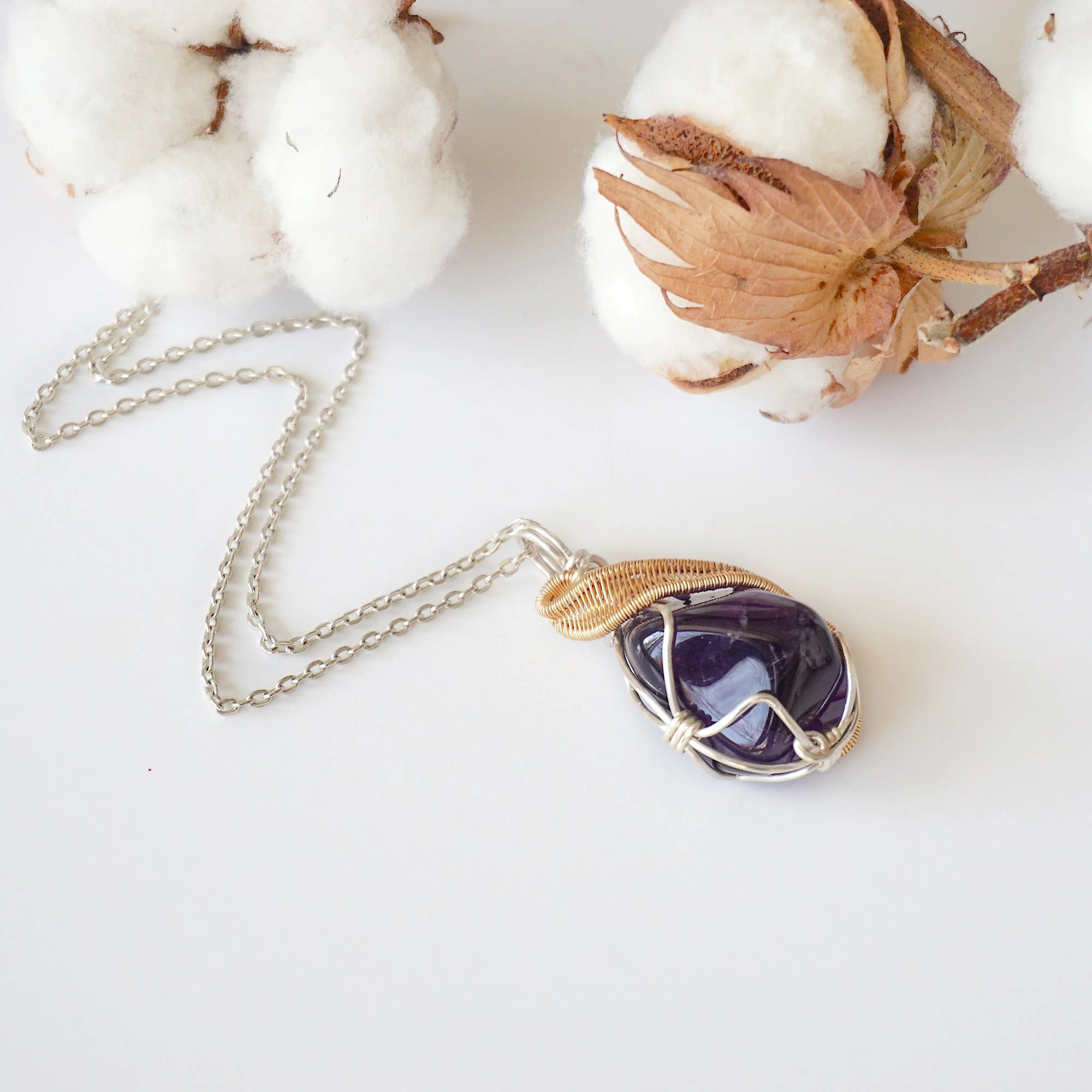 Detailed front view of women’s amethyst necklace, polished dark amethyst pendant, artisan wire wrapped in silver and gold plated copper