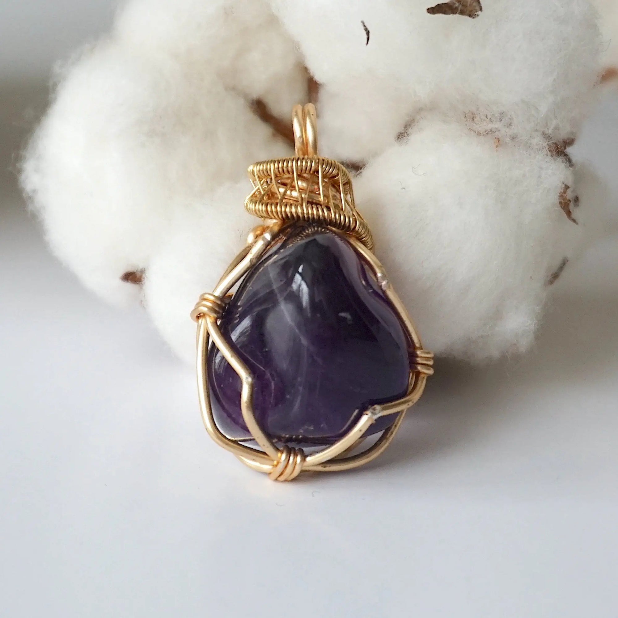 Front side angle of women’s gold amethyst necklace, polished dark amethyst pendant, artisan gold plated copper wire wrap