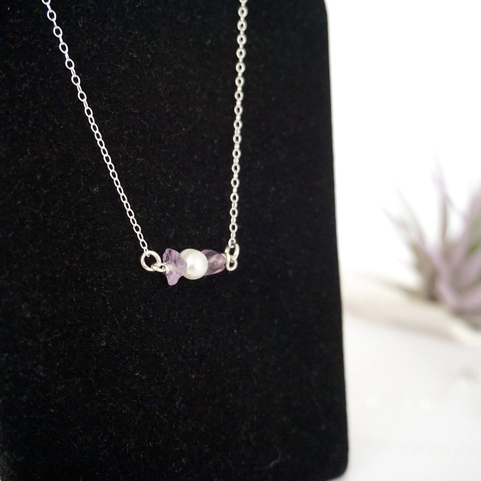 Focused left-side close-up of sterling silver amethyst and pearl bar necklace on jewelry display
