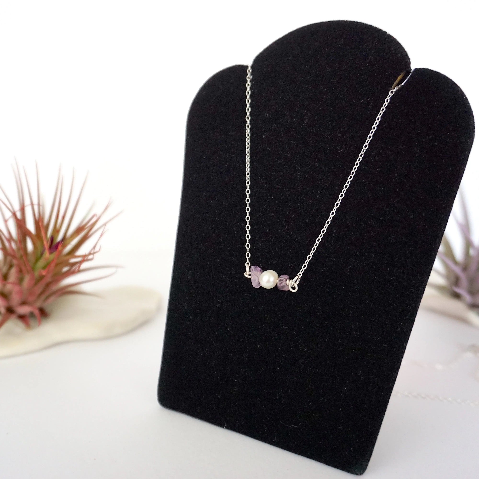 Left angle view of amethyst and pearl bar necklace in 925 sterling silver on jewelry display