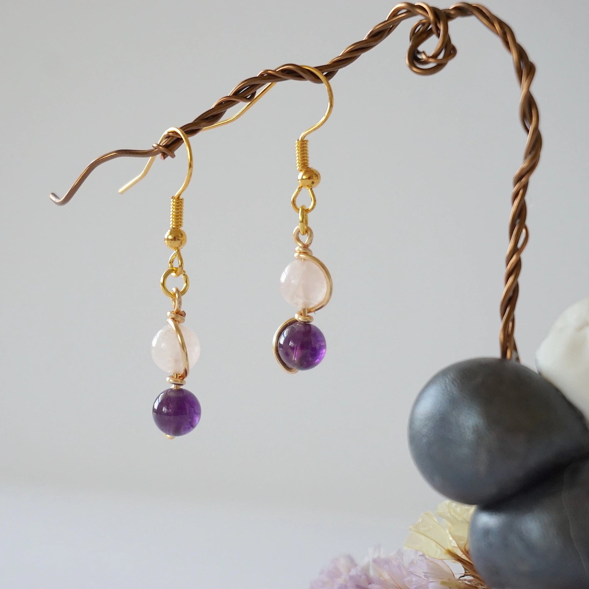 Side view of gold plated copper wire wrapped drop earrings featuring 6mm amethyst bead and 6mm rose quartz bead