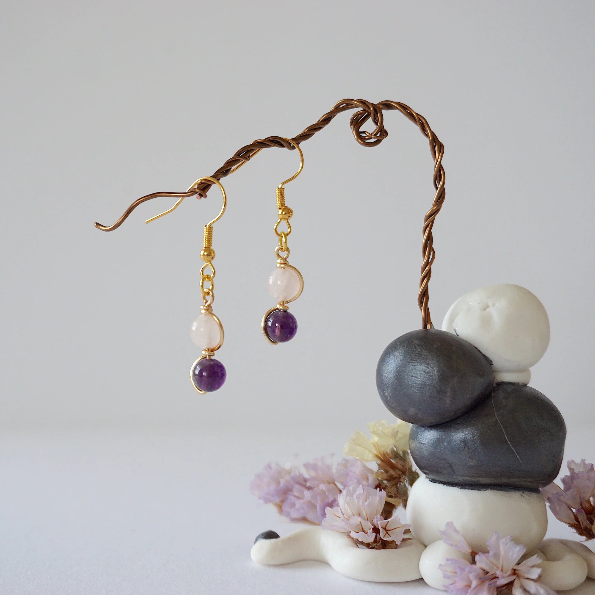 Zoomed out view of minimalist amethyst and rose quartz dangle earrings in gold plated copper with fish hook ear wires