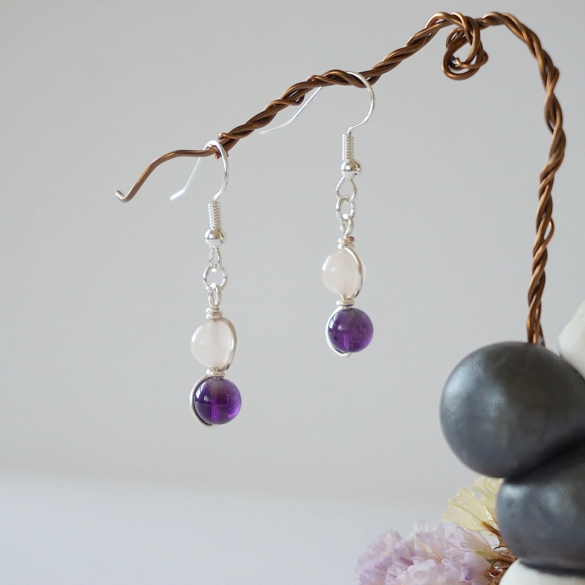 Side view of silver plated copper wire wrapped drop earrings featuring 6mm amethyst bead and 6mm rose quartz bead