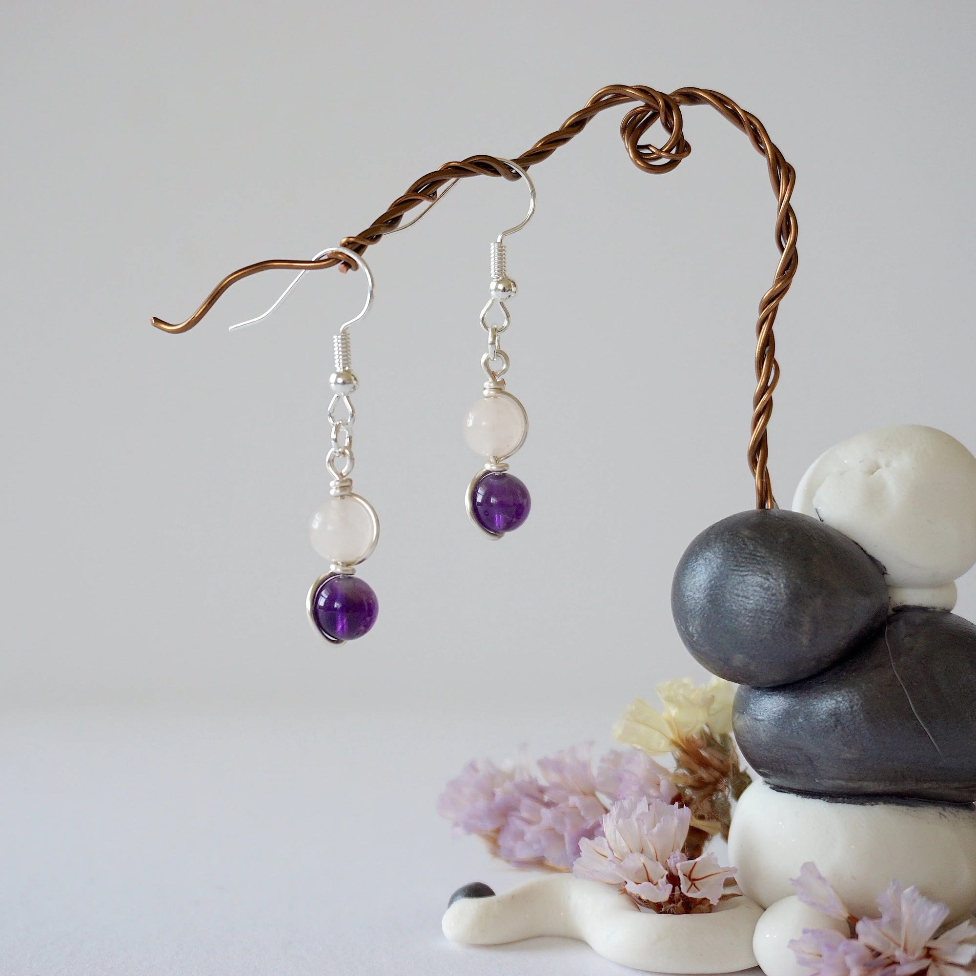 Zoomed out view of minimalist amethyst and rose quartz dangle earrings in silver plated copper with fish hook ear wires