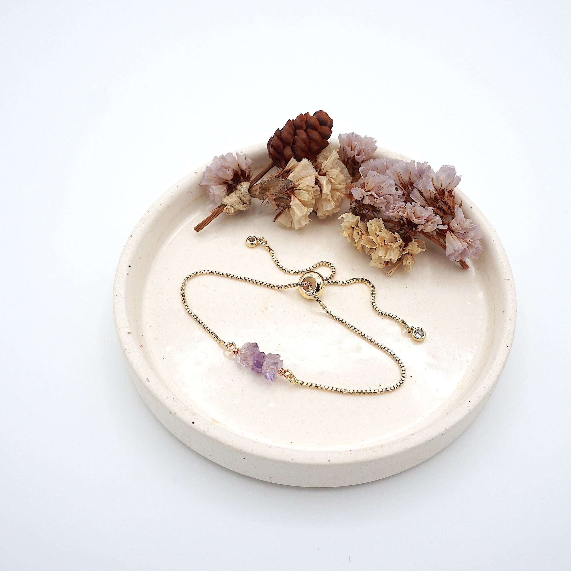 Handmade amethyst bracelet displayed on ceramic tray showing natural purple crystals and gold chain - February birthstone gift for her