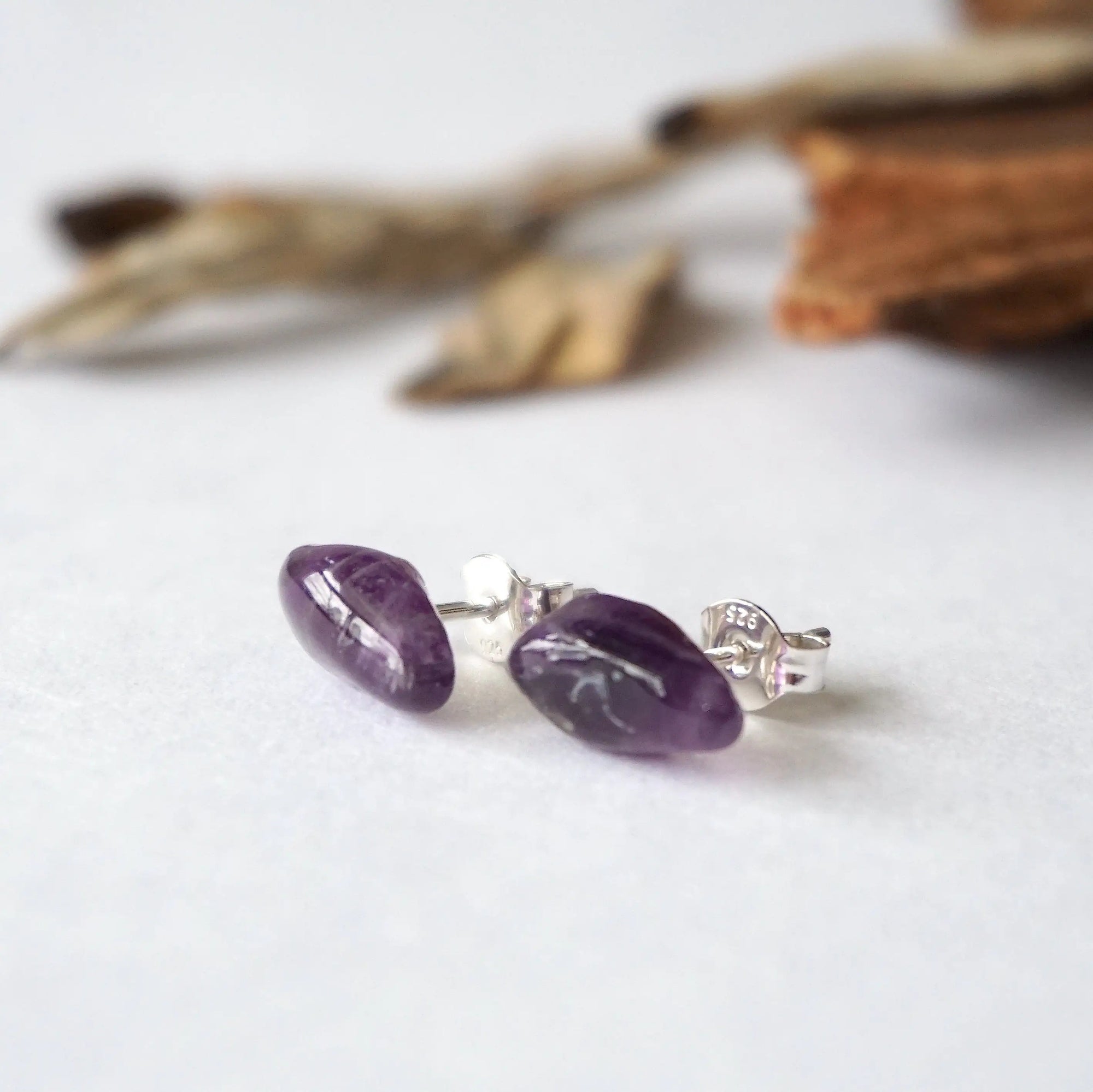 Side angle view of amethyst stud earrings, natural dark amethyst stones, sterling silver posts