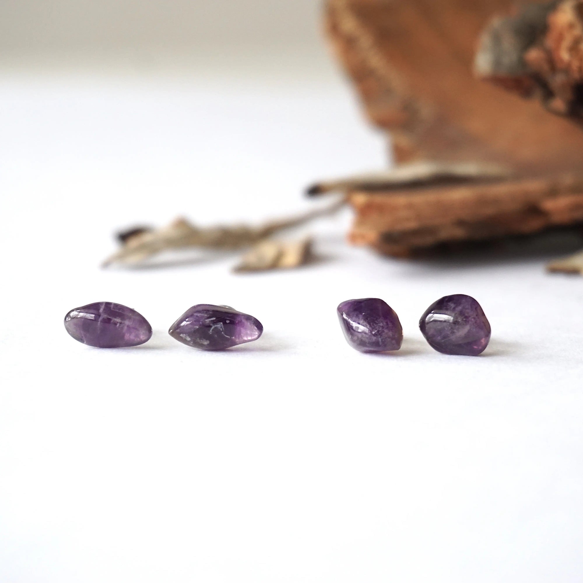 Two pairs of amethyst stud earrings showing natural variation in stone size, shape, and color, sterling silver posts