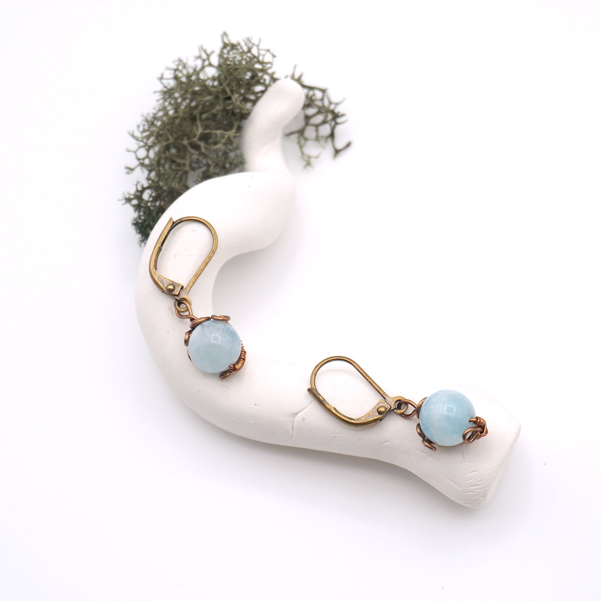 Bird’s eye view of aquamarine drop earrings laying flat on a display, showing detailed wire wrapping and gemstone color.