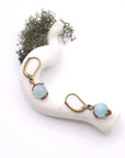 Bird’s eye view of aquamarine drop earrings laying flat on a display, showing detailed wire wrapping and gemstone color.