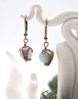 Close-up of handcrafted aquamarine drop earrings with antique bronze copper wire wrapping.