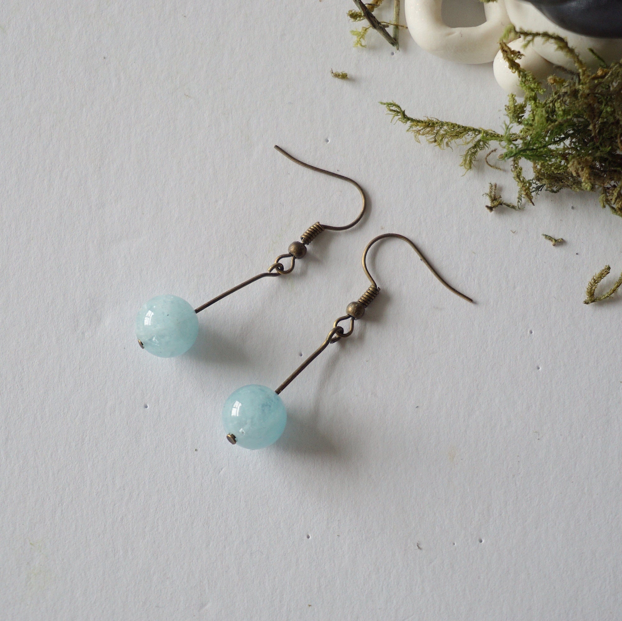 Aquamarine drop earrings laying flat, showing all details and earring hook, antique bronze finish