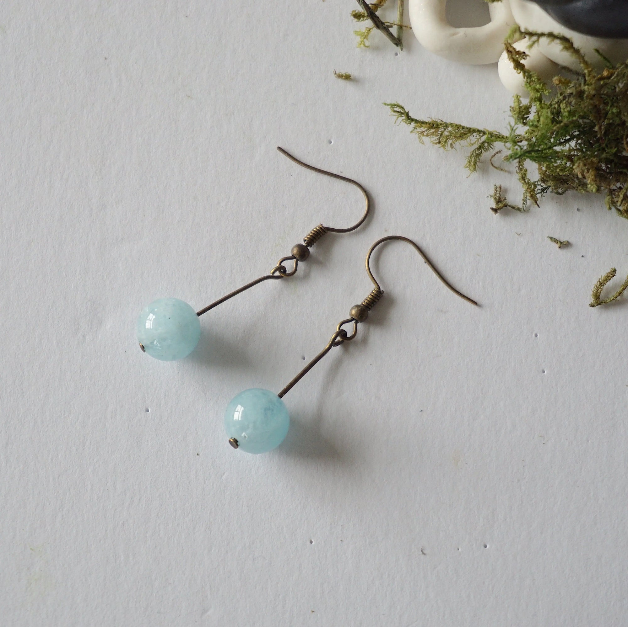 Aquamarine drop earrings laying flat, showing all details and earring hook, antique bronze finish