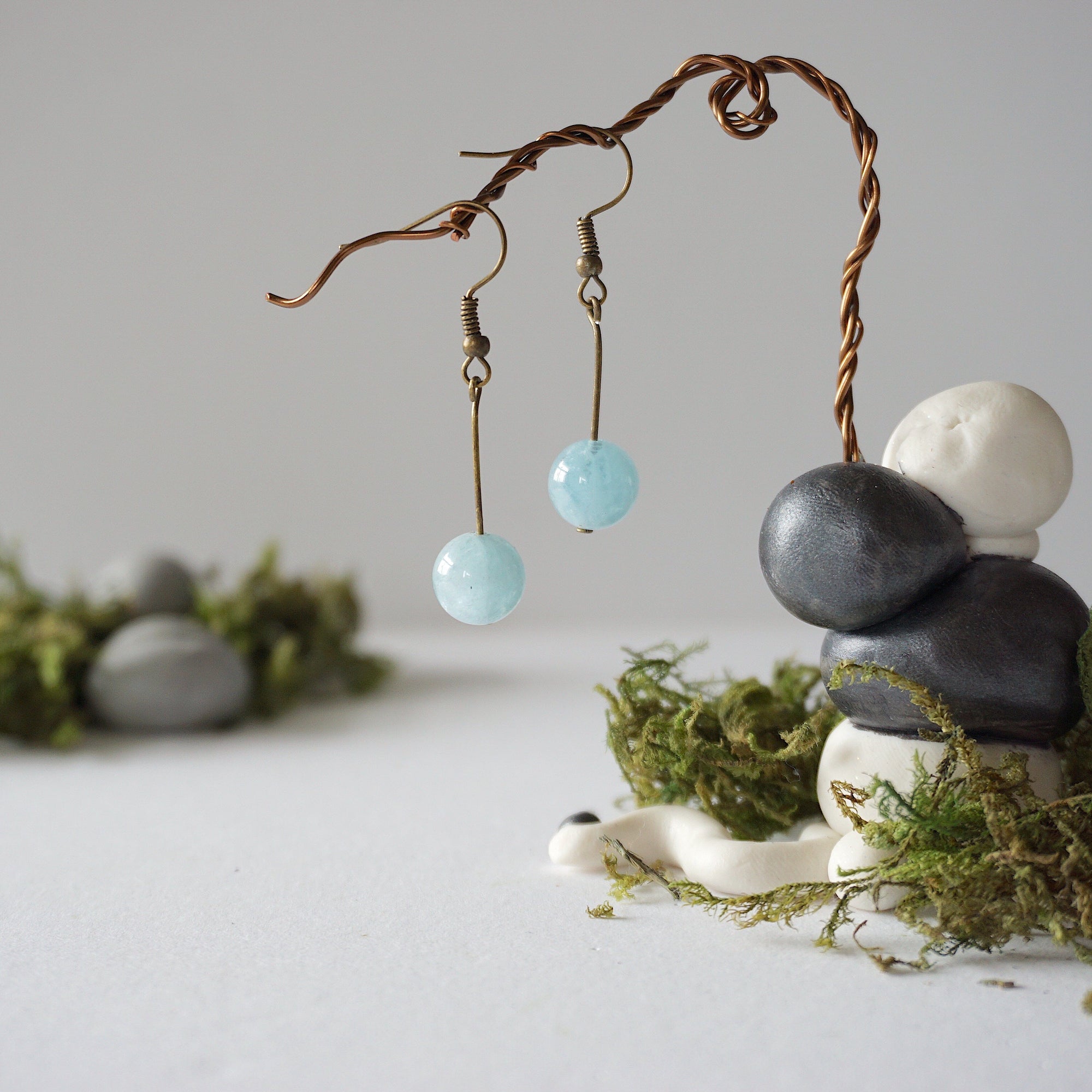 Aquamarine drop earrings on display, angled view, simple artisan design, antique bronze finish