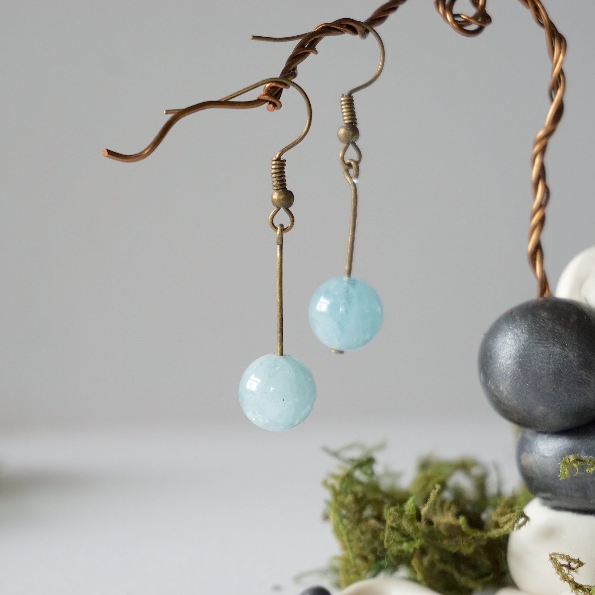 Side angle of minimalist aquamarine drop earrings on display, genuine 10mm aquamarine bead