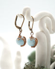 Side angle of aquamarine drop earrings on a display stand, highlighting antique bronze copper wire wrapping.