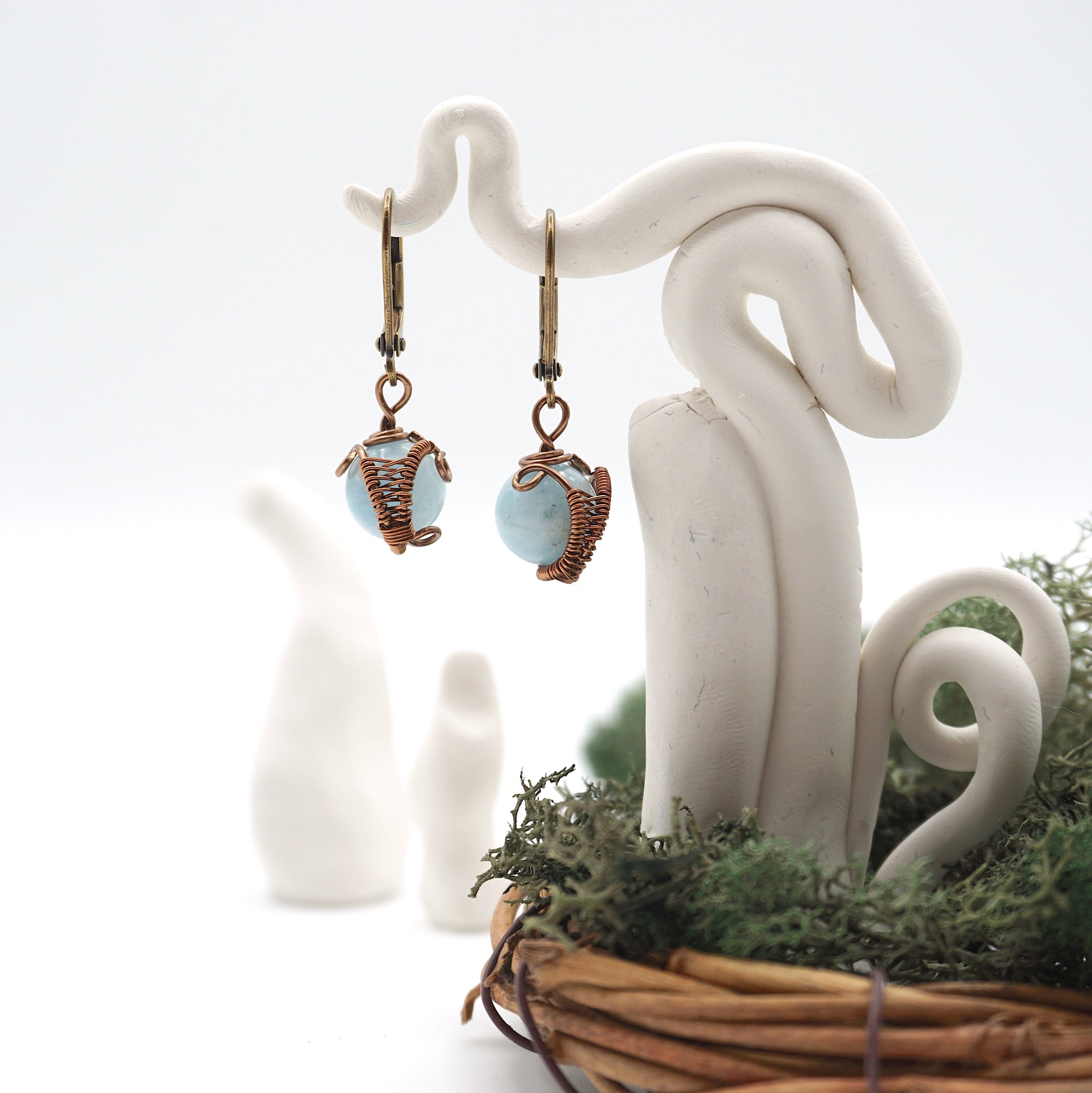 Front angle of aquamarine drop earrings hanging on a jewelry display, wire-wrapped design.