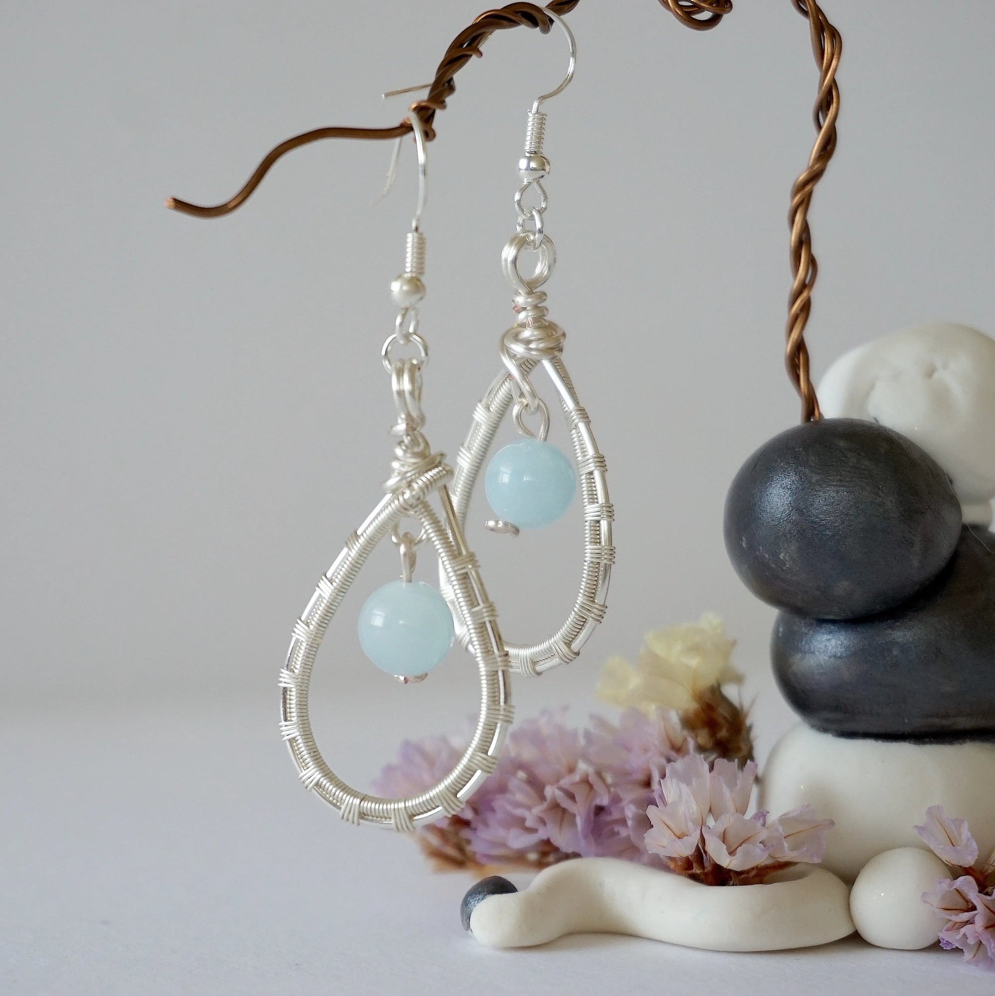 Side angle of aquamarine earrings, showing detailed wire wrapping and genuine gemstone, soft silver finish