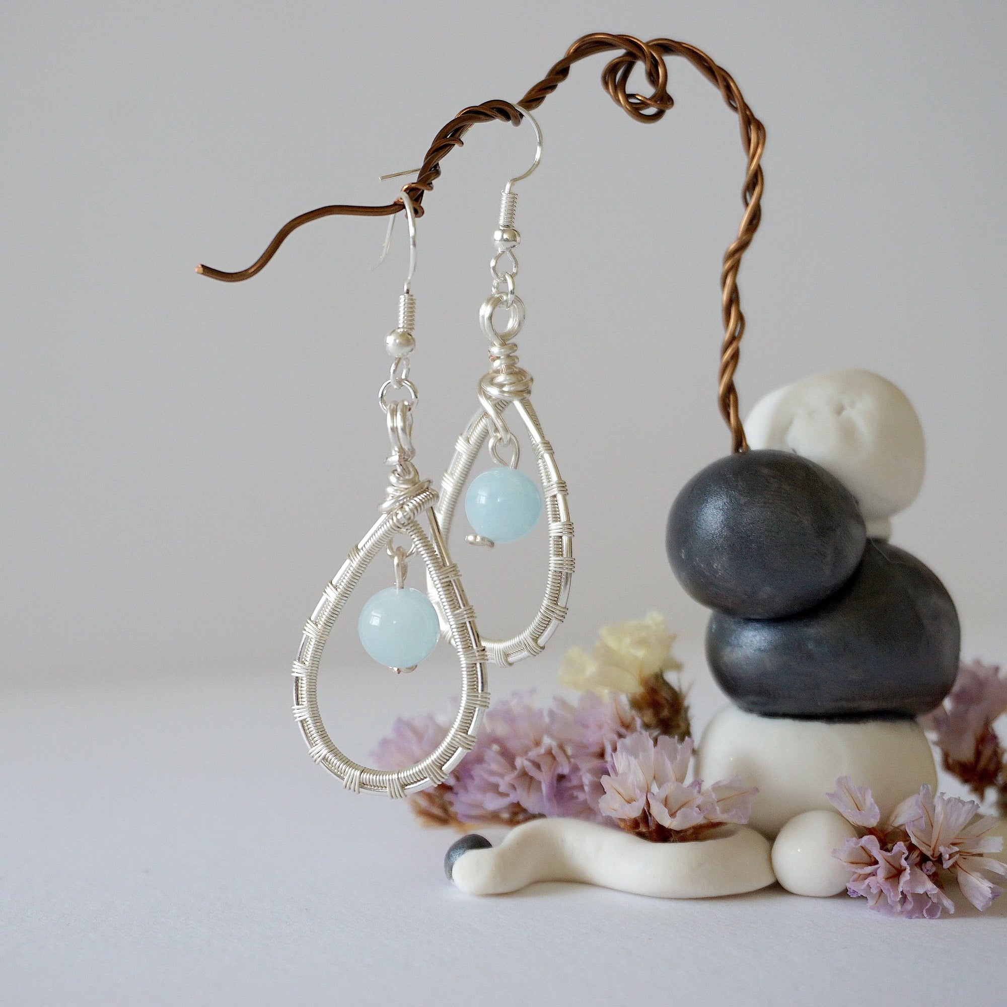 Zoomed out look at aquamarine earrings, artisan wire wrapped, soft silver finish, March birthstone