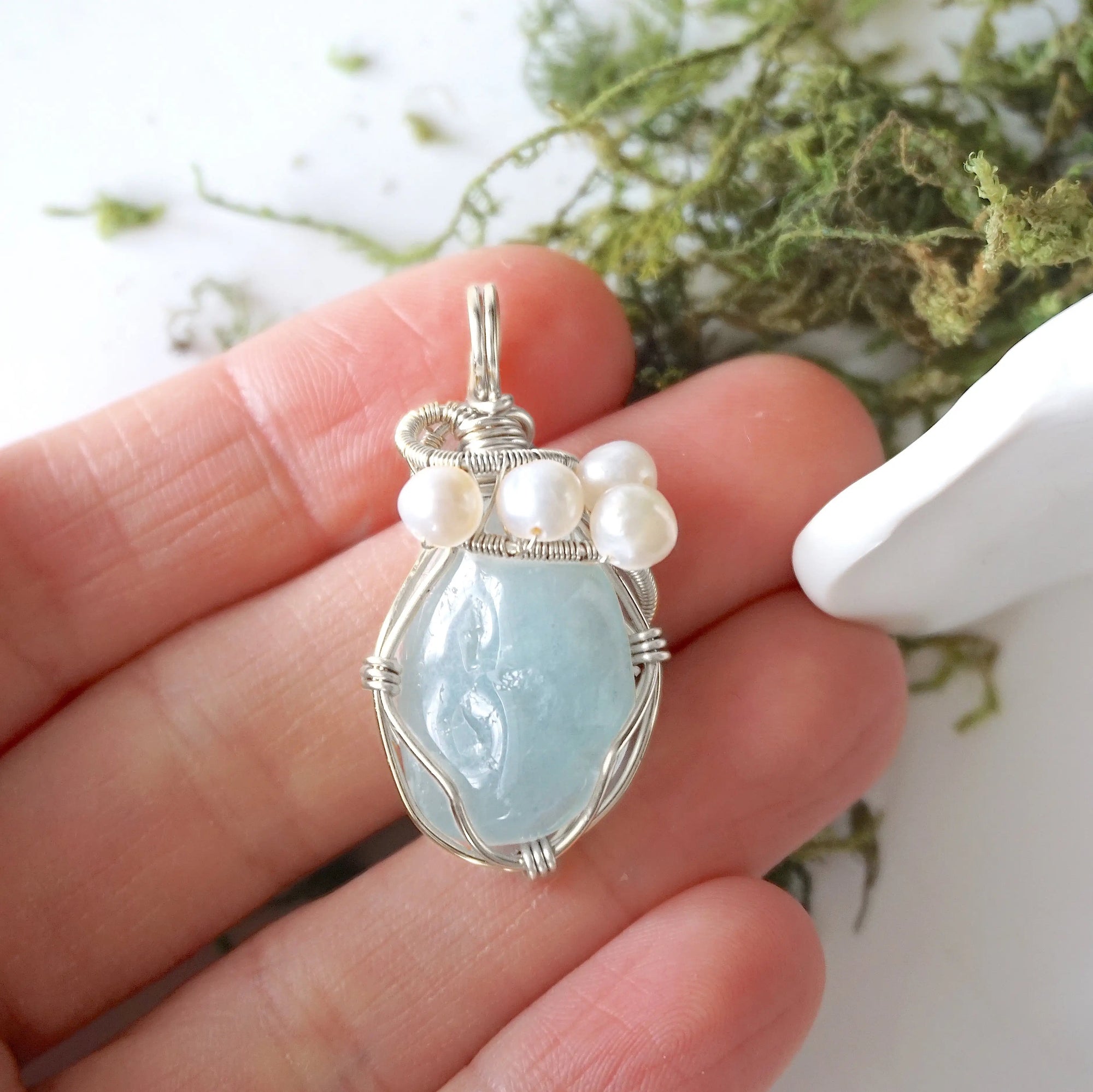 Aquamarine and freshwater pearl pendant necklace in hand for size reference, silver wire wrapped, handcrafted gemstone jewelry