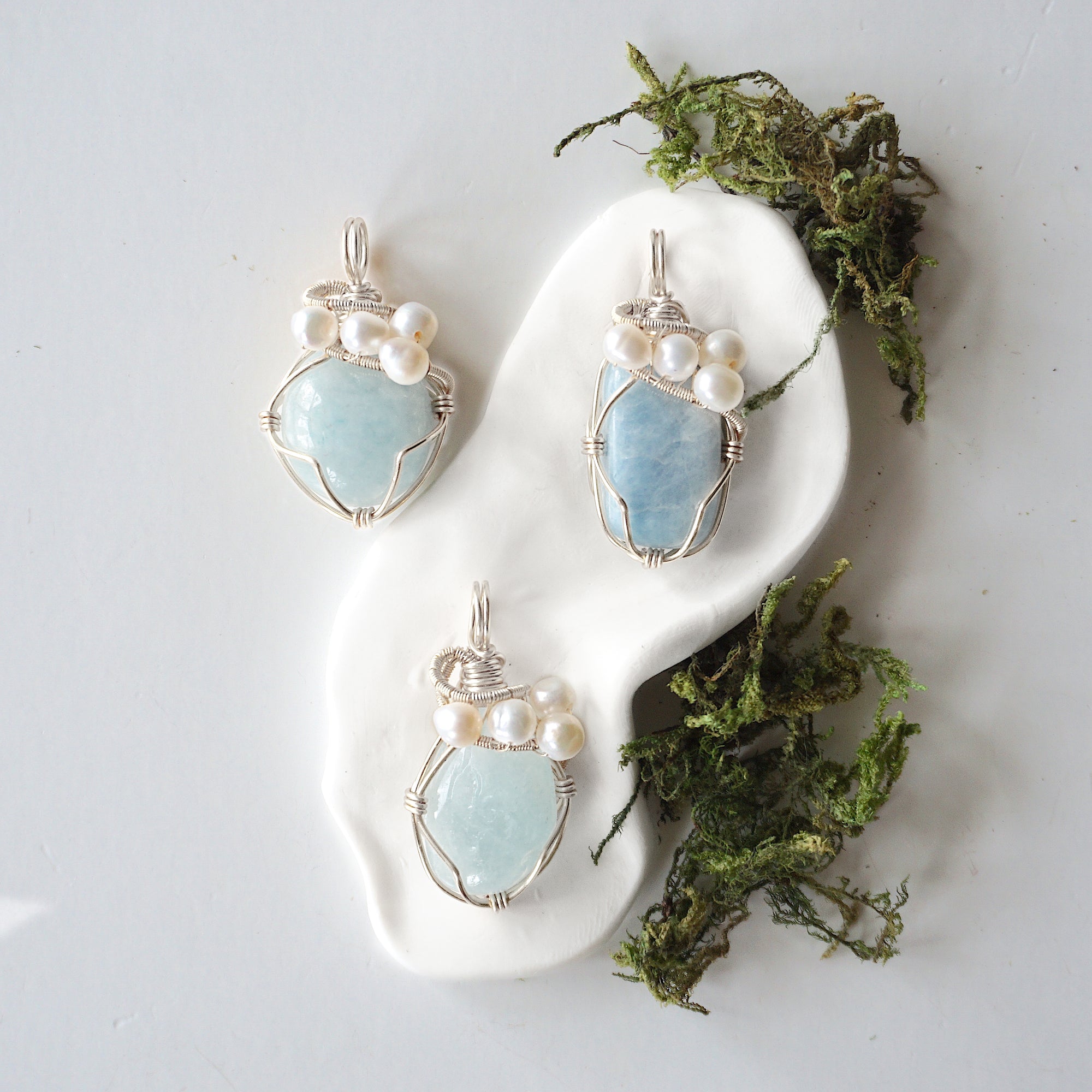 Three silver wire wrapped aquamarine and freshwater pearl pendants showing natural stone variation, artisan jewelry for women