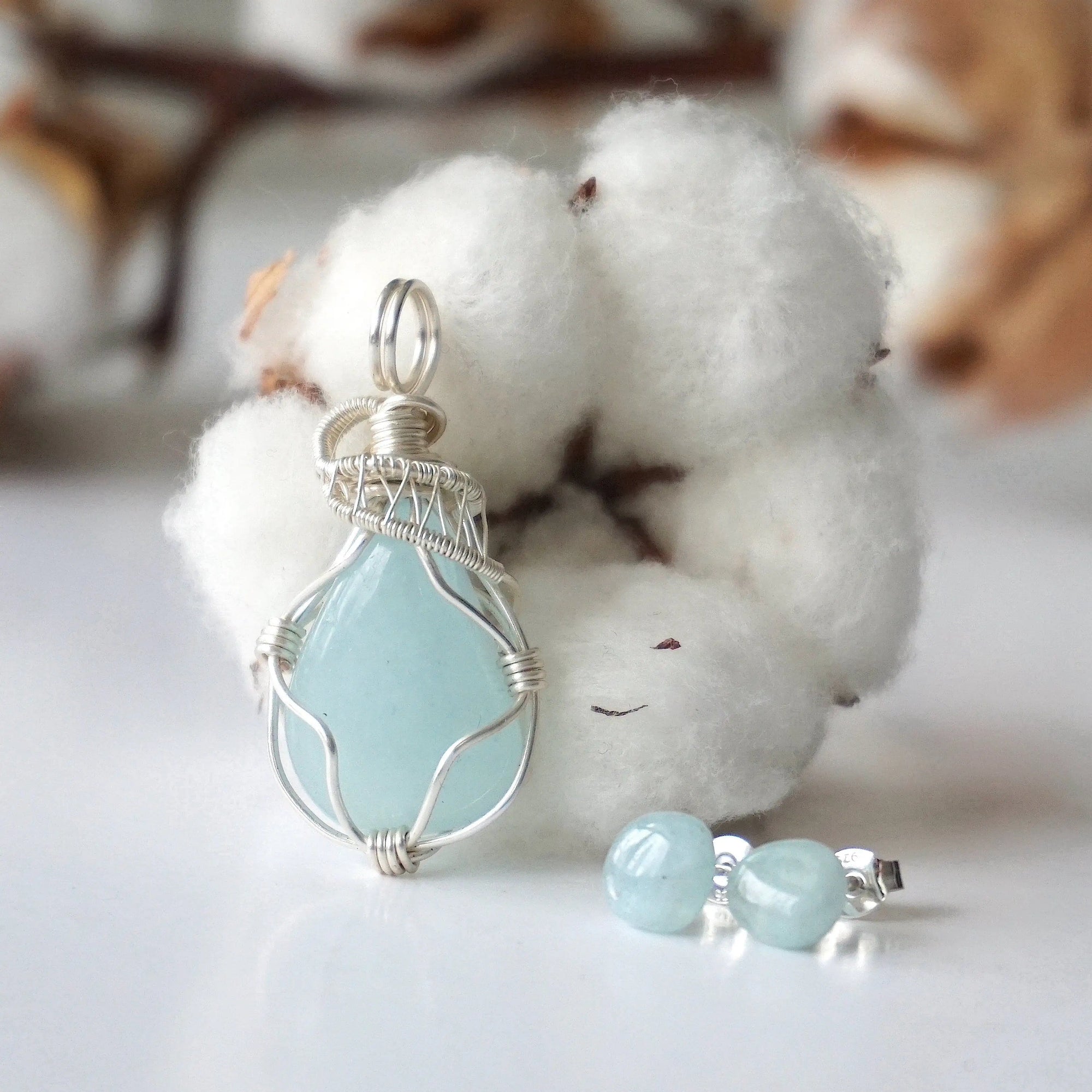 Detailed front angle of aquamarine jewelry set, showing wire wrapped pendant and minimalist stud earrings, soft silver finish, genuine aquamarine
