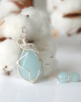 Detailed side angle of aquamarine jewelry set, artisan wire wrapped necklace and raw aquamarine stud earrings, soft silver finish