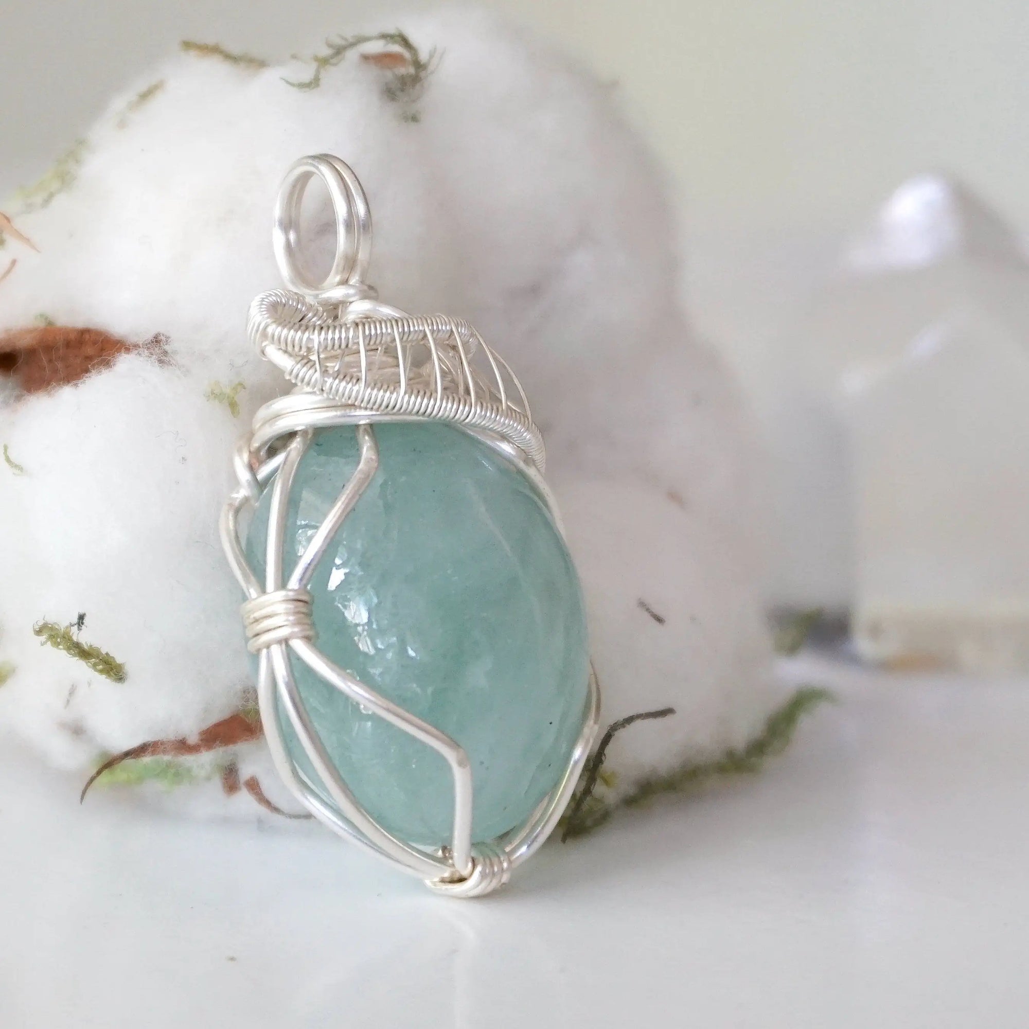 Side angle of aquamarine pendant showing artisan wire wrapping details, soft silver over copper