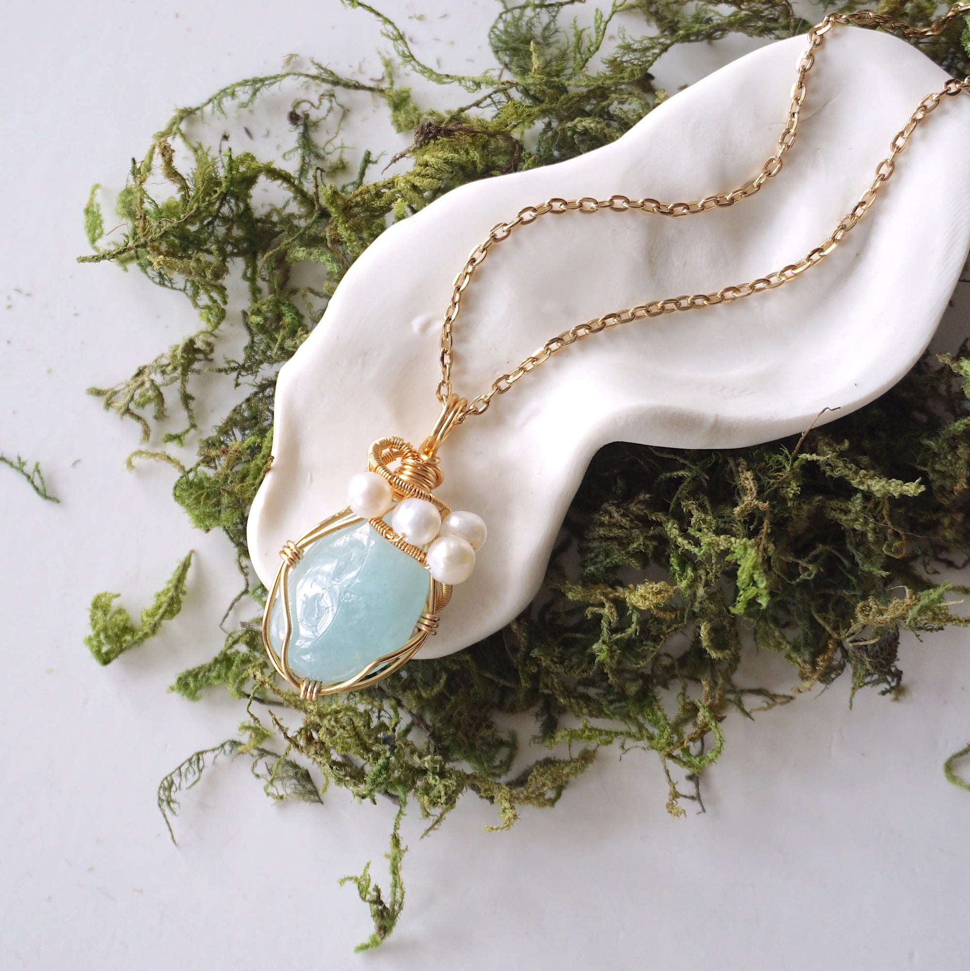 Aquamarine and freshwater pearl pendant on gold plated brass chain laying flat, handmade wire wrapped jewelry for women