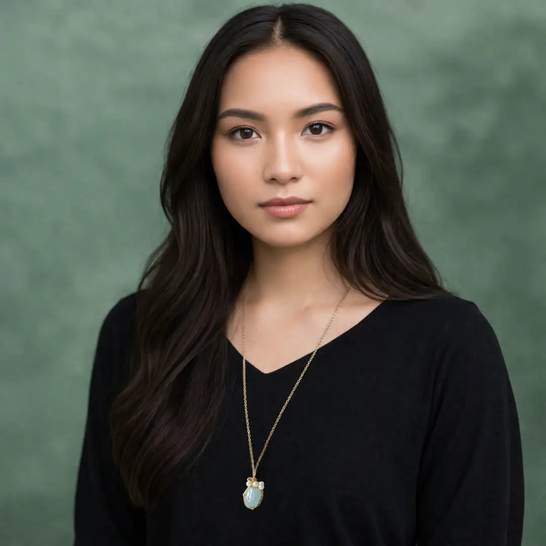 Model wearing aquamarine and freshwater pearl pendant on gold plated brass chain.