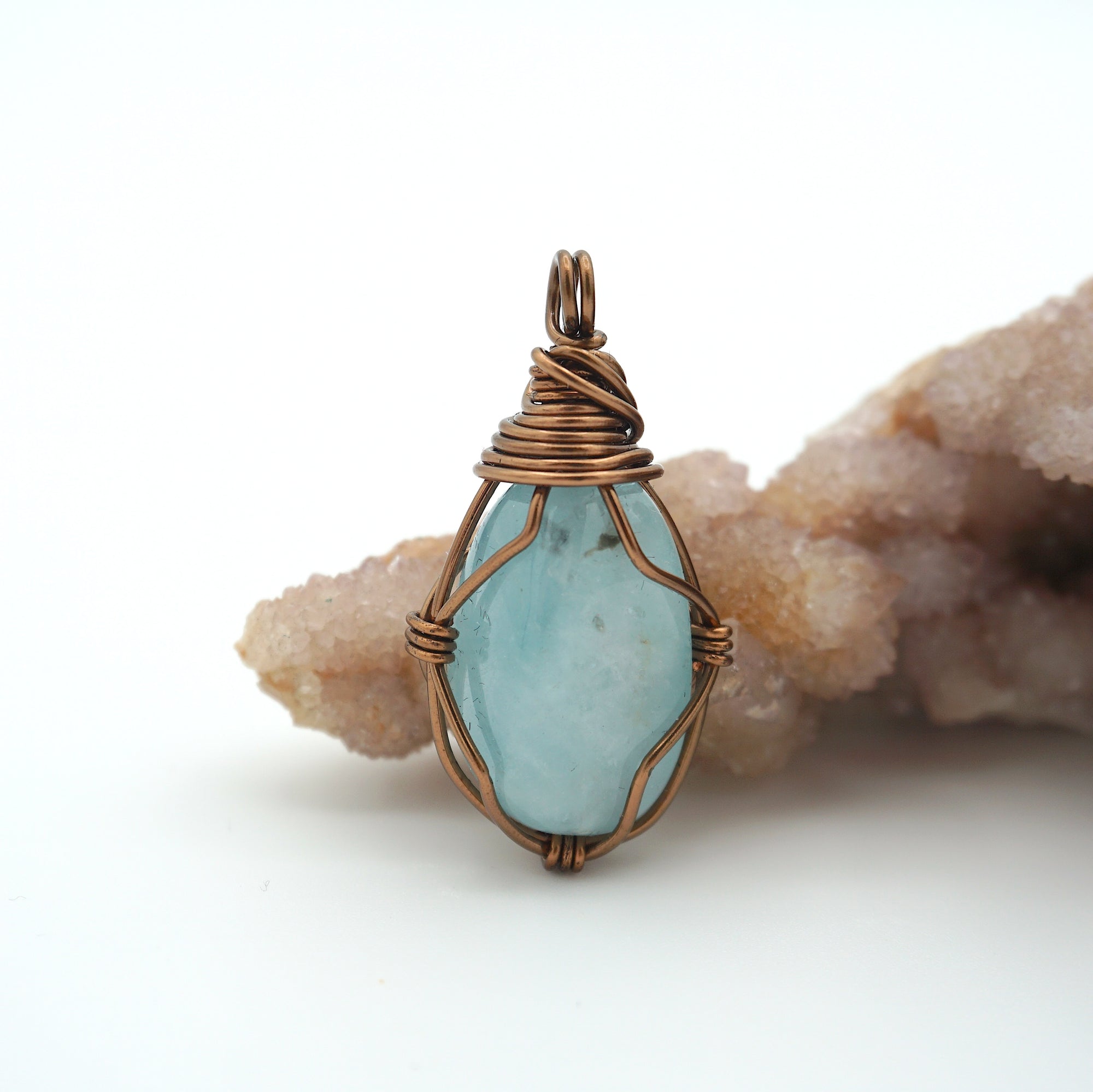 Close-up of aquamarine pendant front, polished gemstone in simple artisan antique bronze wire wrapping