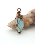 Side view of aquamarine pendant showing artisan wire wrapping and natural crystal shape, antique bronze finish