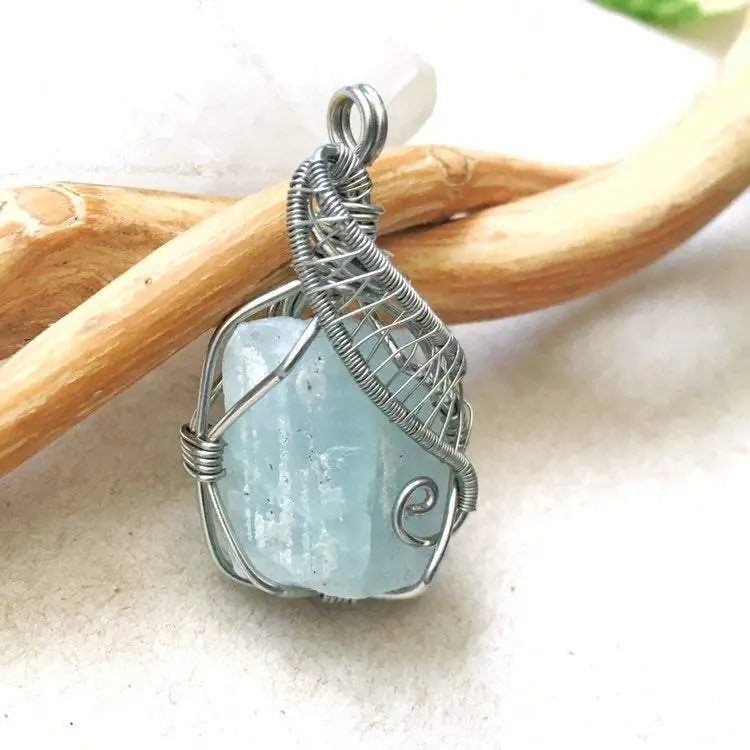 Close-up of aquamarine pendant front, raw gemstone in detailed artisan dark silver wire wrapping