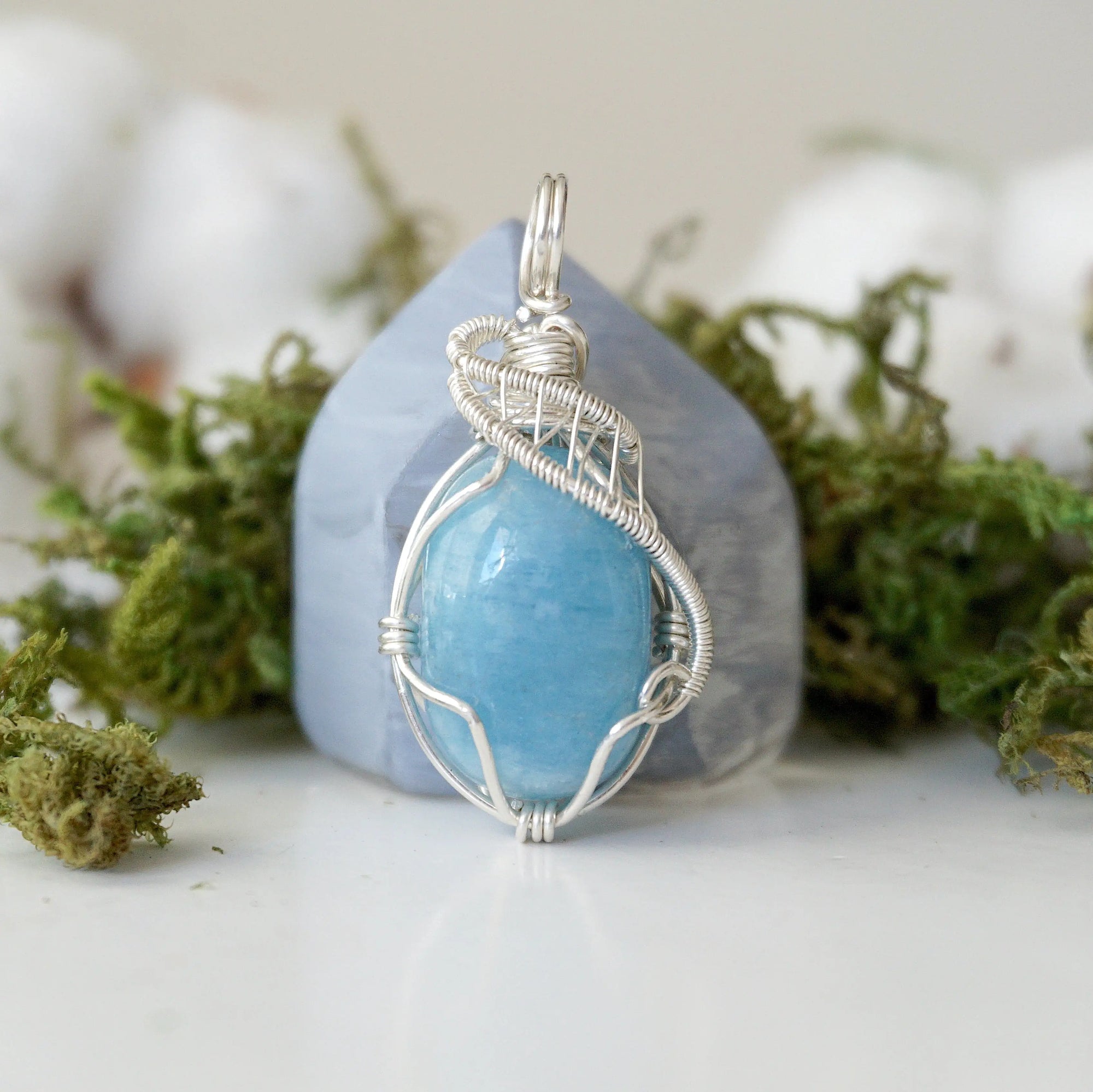 Close-up of aquamarine pendant front, polished gemstone in detailed 925 sterling silver wire wrapping