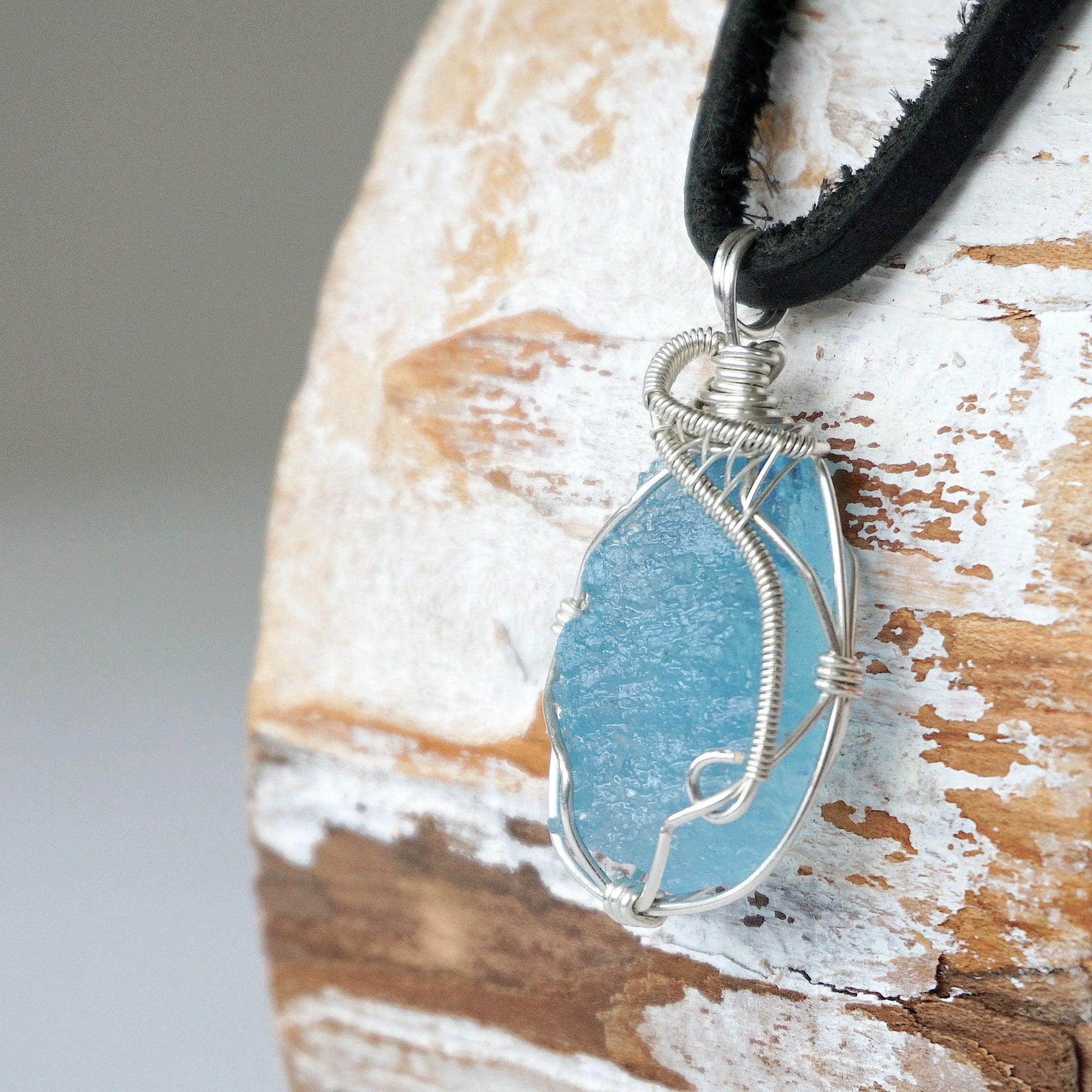 Left side view of raw aquamarine pendant showing detailed artisan wire wrapping in sterling silver, men's design