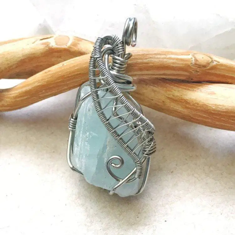 Side view of raw aquamarine pendant showing detailed artisan wire wrapping in dark silver