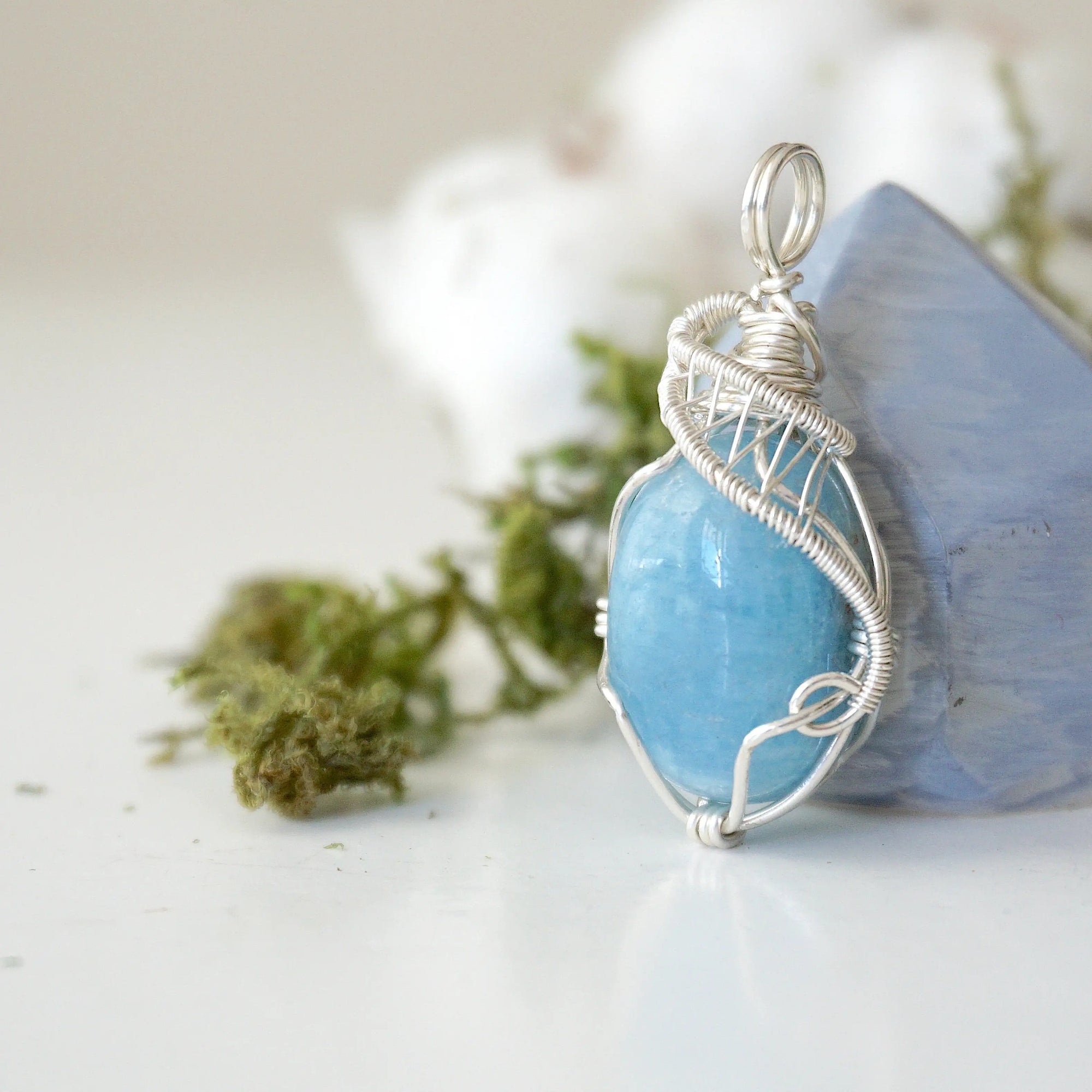 Left side view of aquamarine pendant showing intricate artisan wire wrapping and natural crystal shape