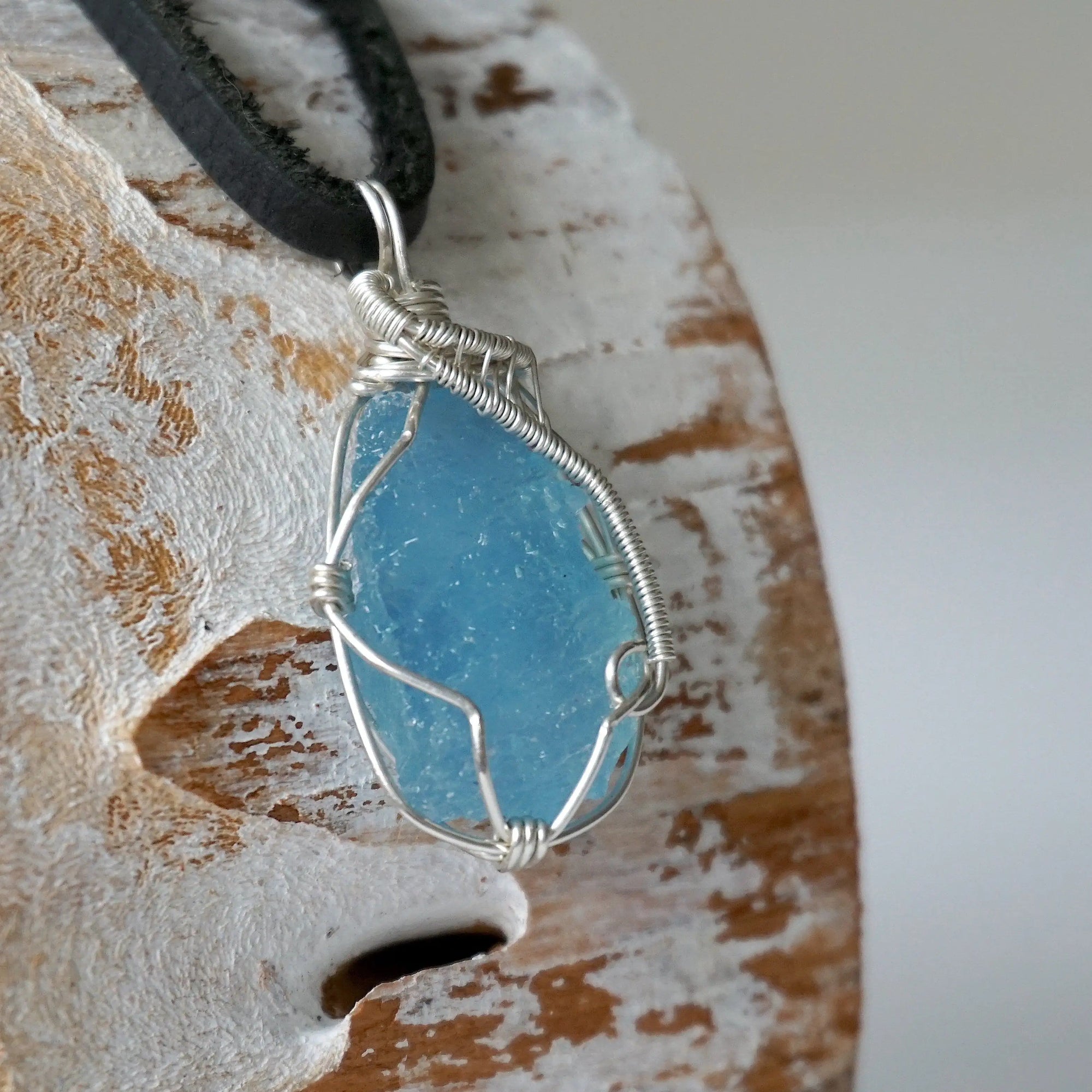 Right side view of raw aquamarine pendant showing detailed artisan wire wrapping in sterling silver, men's design